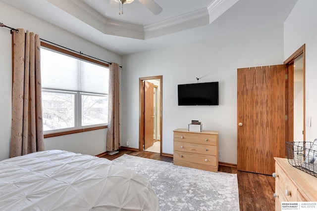 bedroom featuring dark wood-style floors, a tray ceiling, crown molding, a ceiling fan, and baseboards