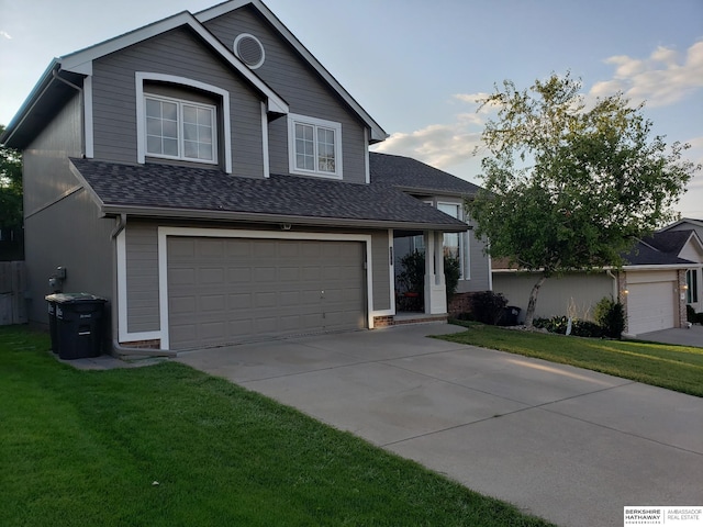 traditional-style house featuring an attached garage, roof with shingles, concrete driveway, and a front yard