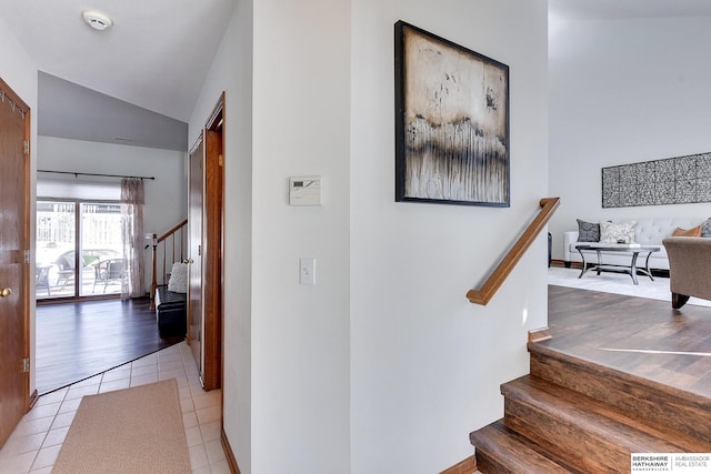 hallway with stairs, vaulted ceiling, and light tile patterned flooring