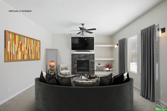 living area featuring light carpet, ceiling fan, a fireplace, and baseboards