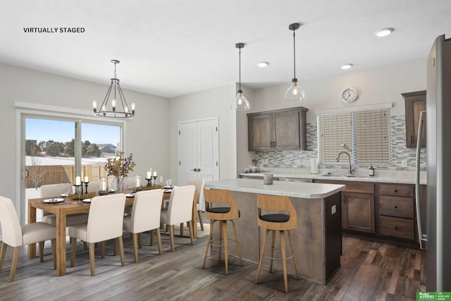 kitchen with hanging light fixtures, a kitchen island, a sink, and freestanding refrigerator