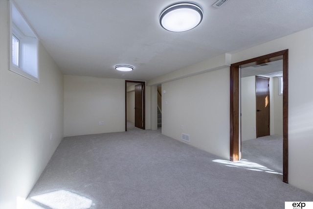 basement with carpet floors, stairs, and visible vents