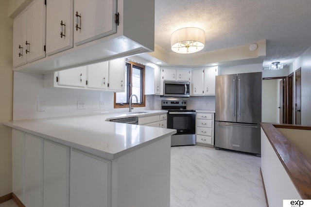 kitchen featuring appliances with stainless steel finishes, marble finish floor, white cabinetry, and a peninsula