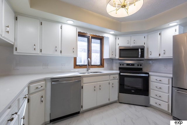 kitchen with marble finish floor, light countertops, appliances with stainless steel finishes, white cabinetry, and a sink