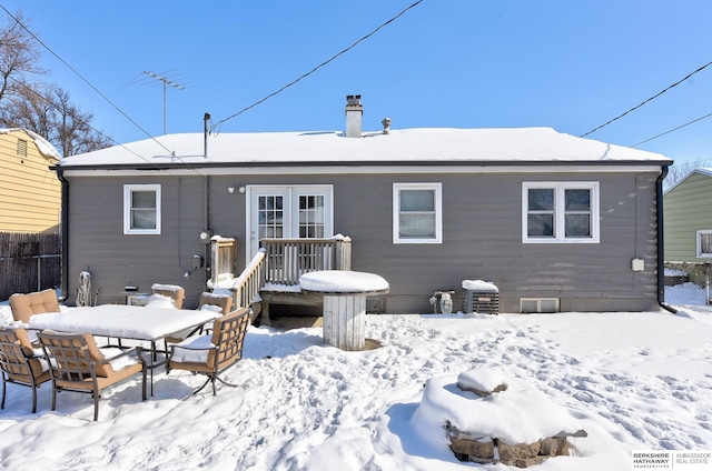 snow covered back of property featuring french doors, crawl space, and fence