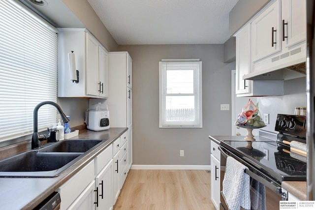 kitchen featuring light wood finished floors, black range with electric stovetop, white cabinetry, a sink, and under cabinet range hood