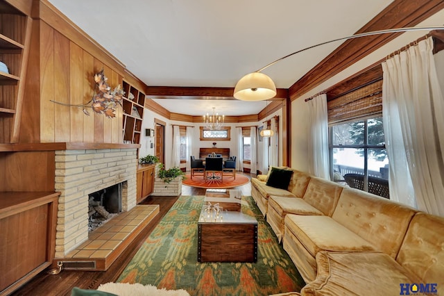 living area with dark wood-style floors, crown molding, a notable chandelier, and a tiled fireplace