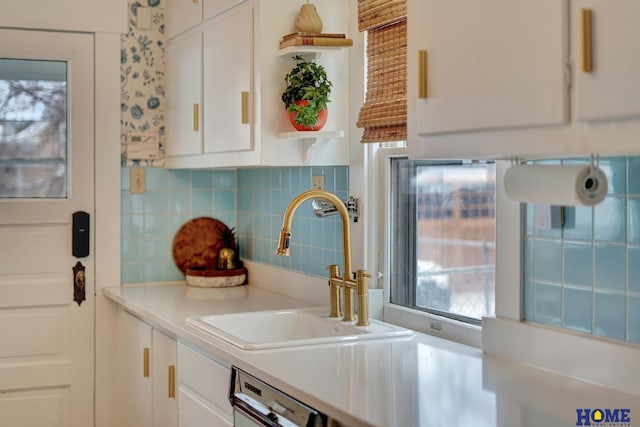 kitchen with a sink, white cabinetry, light countertops, open shelves, and tasteful backsplash