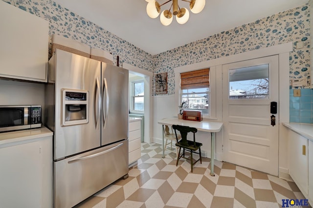 kitchen with stainless steel appliances, light floors, light countertops, and wallpapered walls