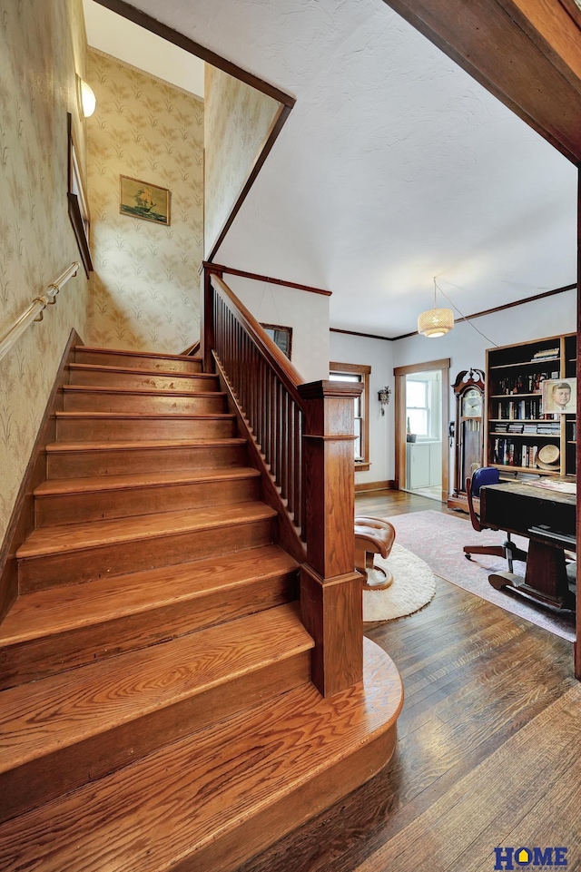 stairs with wallpapered walls and wood finished floors