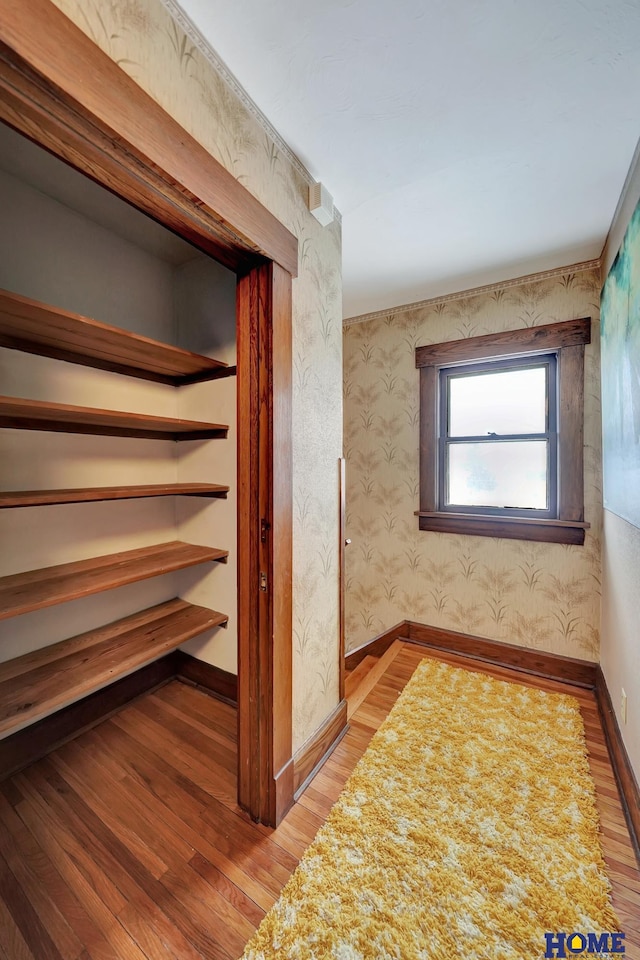 hall with baseboards, wood finished floors, and wallpapered walls