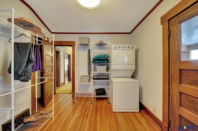 clothes washing area featuring laundry area, baseboards, stacked washer and clothes dryer, ornamental molding, and light wood-style floors