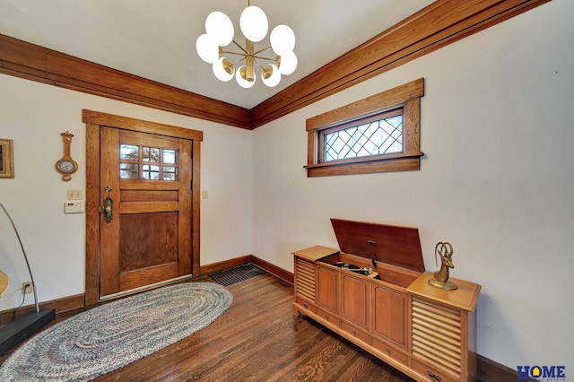 entrance foyer featuring an inviting chandelier, baseboards, ornamental molding, and dark wood finished floors