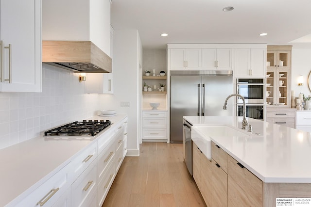 kitchen with custom range hood, glass insert cabinets, stainless steel appliances, light countertops, and white cabinetry