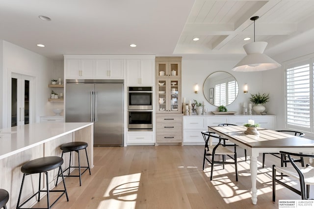 kitchen with pendant lighting, open shelves, appliances with stainless steel finishes, glass insert cabinets, and white cabinets