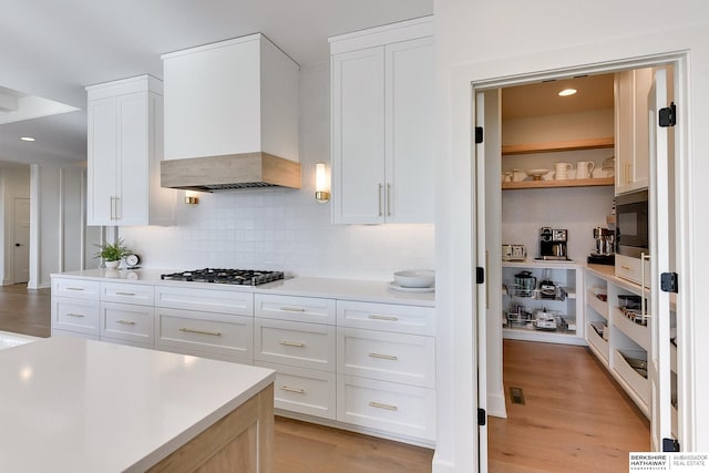 kitchen featuring open shelves, light countertops, custom range hood, backsplash, and white cabinets