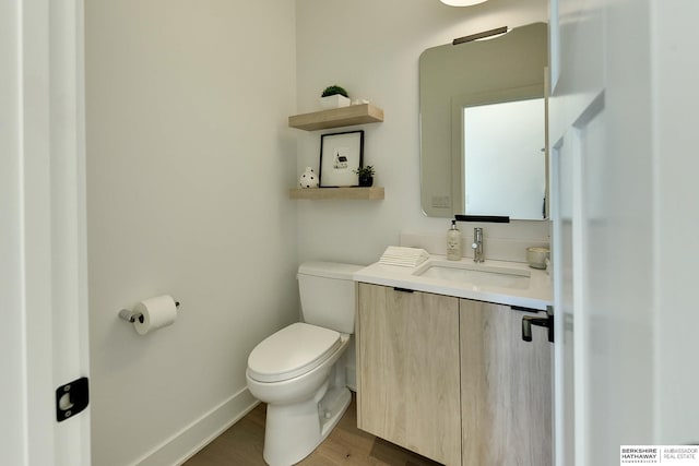 bathroom with baseboards, vanity, toilet, and wood finished floors