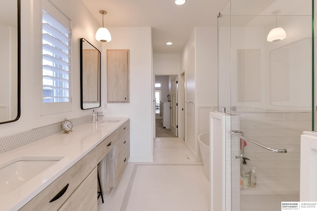 full bath with a sink, tile patterned flooring, double vanity, and a wealth of natural light