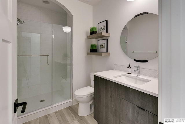 bathroom featuring vanity, a stall shower, wood finished floors, and toilet