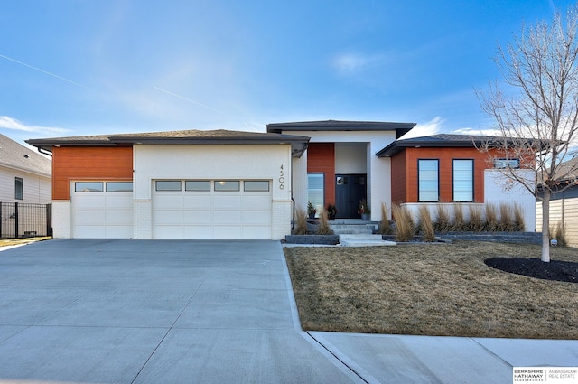 view of front facade with a garage, concrete driveway, brick siding, and stucco siding