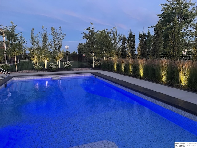 pool at dusk with fence and a fenced in pool