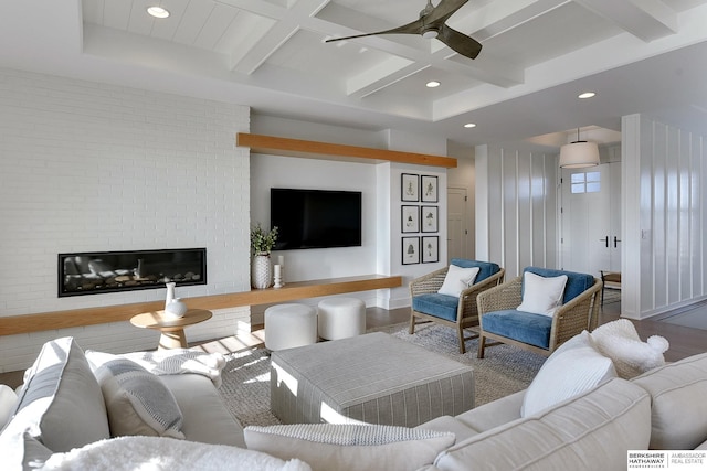 living room with wood finished floors, a glass covered fireplace, beam ceiling, and a ceiling fan