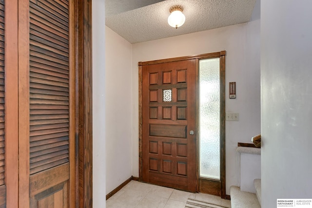 entrance foyer featuring a textured ceiling, light tile patterned flooring, stairs, and baseboards