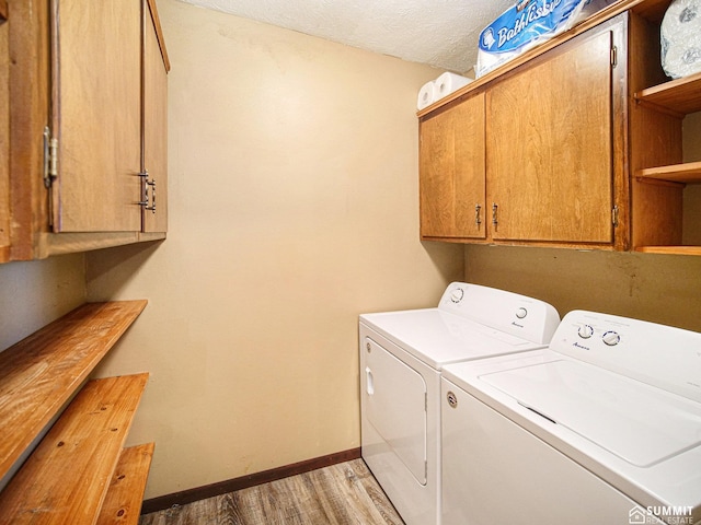 washroom featuring washing machine and clothes dryer, cabinet space, light wood-style flooring, a textured ceiling, and baseboards