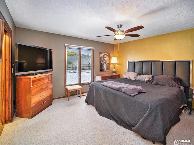 bedroom featuring light carpet, baseboards, a ceiling fan, and a textured ceiling