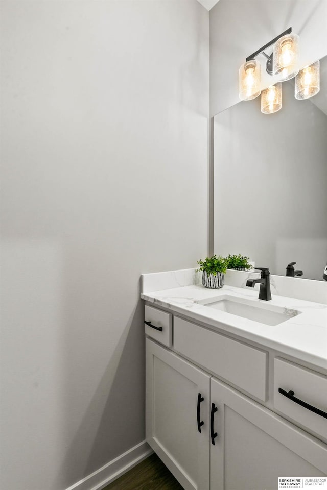 bathroom with wood finished floors, vanity, and baseboards