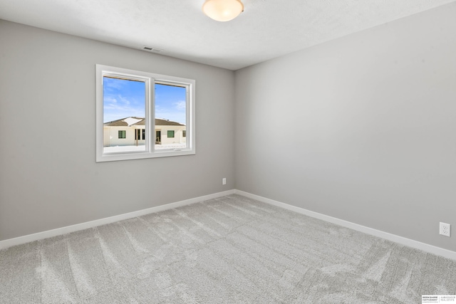 carpeted spare room featuring visible vents and baseboards