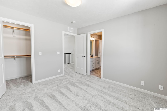 unfurnished bedroom with light colored carpet, visible vents, baseboards, a closet, and a walk in closet