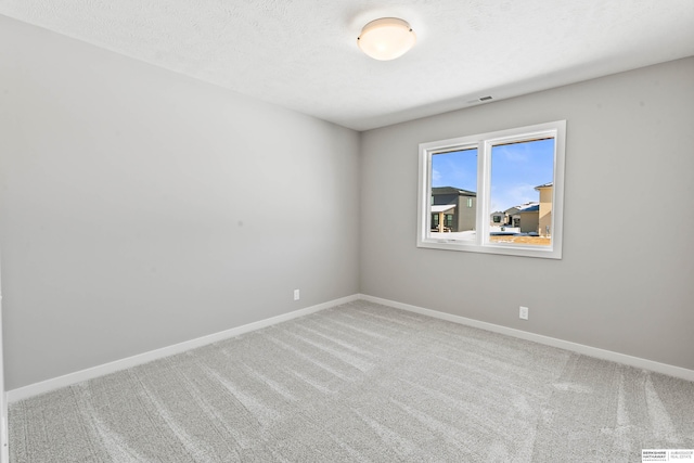 unfurnished room featuring carpet floors, visible vents, baseboards, and a textured ceiling