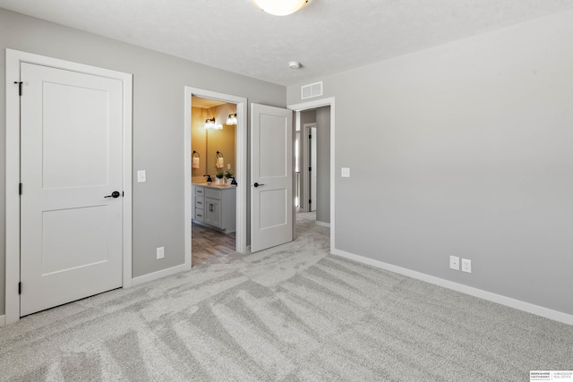 unfurnished bedroom with light carpet, connected bathroom, visible vents, and baseboards