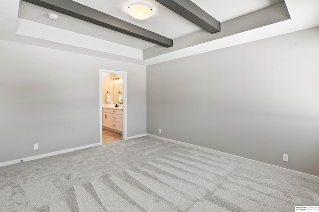 unfurnished bedroom featuring light carpet, connected bathroom, beam ceiling, and baseboards