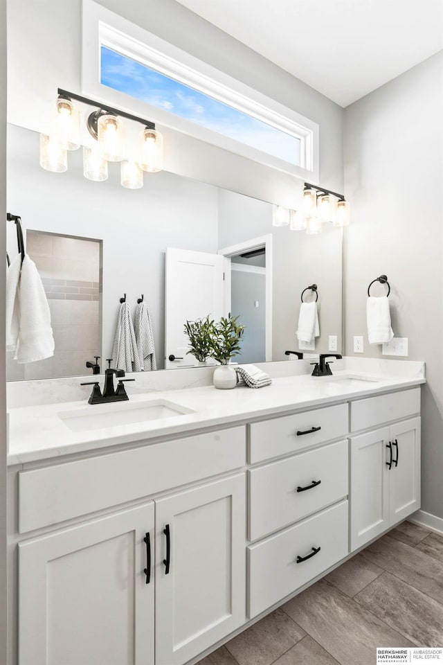 full bathroom with double vanity, a sink, and wood finished floors