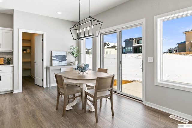 dining area featuring dark wood-style floors, visible vents, baseboards, and an inviting chandelier