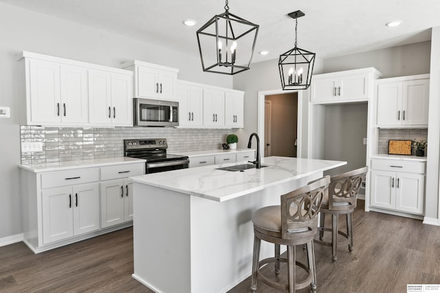 kitchen featuring appliances with stainless steel finishes, white cabinets, a sink, and an island with sink