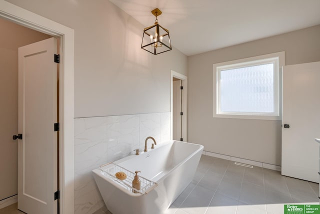 full bathroom featuring a wainscoted wall, a freestanding tub, tile walls, and an inviting chandelier