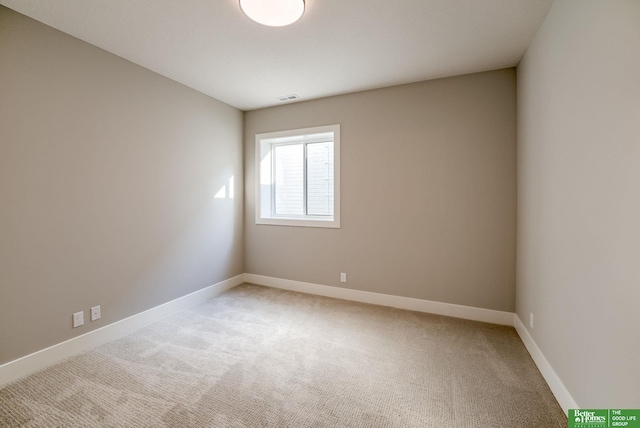 spare room with light colored carpet, visible vents, and baseboards