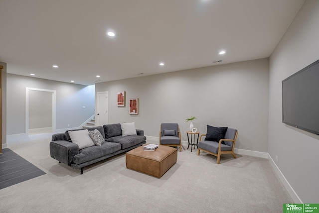 living area featuring recessed lighting, light carpet, baseboards, and stairs