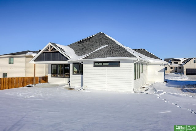 view of front of property with a shingled roof and fence