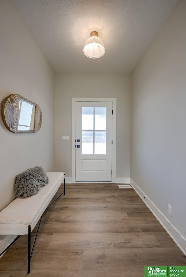 doorway featuring baseboards, visible vents, and light wood finished floors