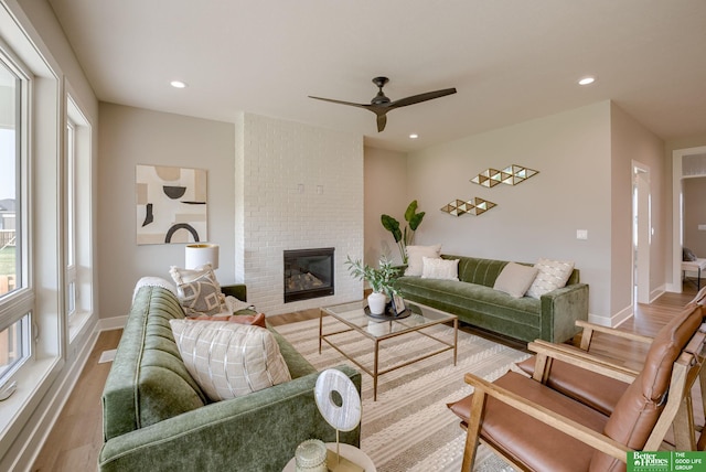 living room with light wood finished floors, baseboards, a ceiling fan, a fireplace, and recessed lighting