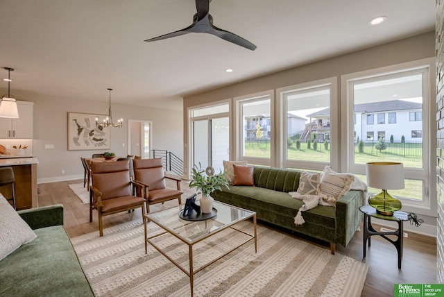 living area featuring recessed lighting, light wood-style flooring, baseboards, and ceiling fan with notable chandelier