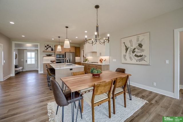 dining room featuring light wood finished floors, baseboards, an inviting chandelier, and recessed lighting