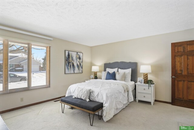 bedroom featuring light carpet, a textured ceiling, and baseboards