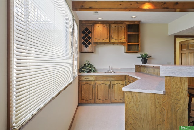 kitchen featuring brown cabinets, a peninsula, light countertops, and a sink