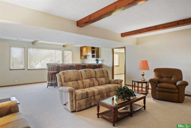 living room featuring light carpet, beamed ceiling, bar, and baseboards