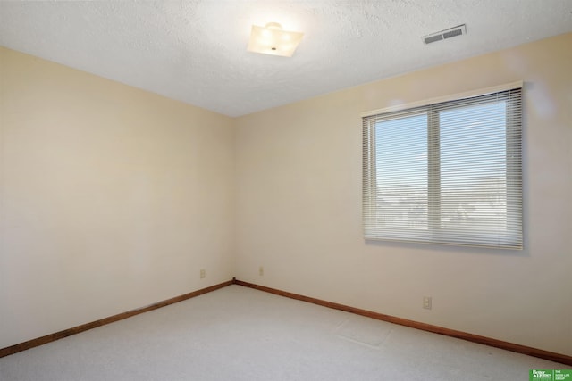 empty room with light carpet, a textured ceiling, visible vents, and baseboards